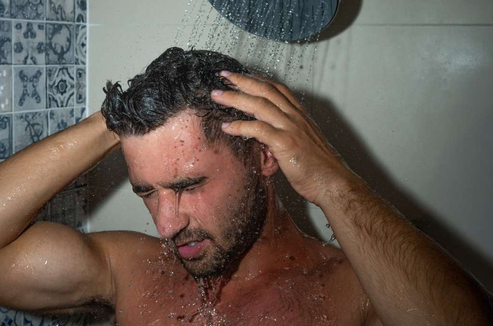 Man massaging scalp under filtered shower
